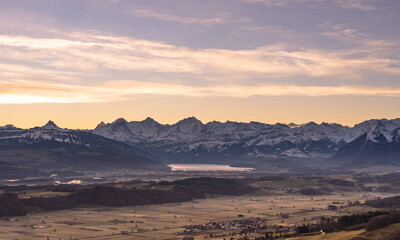 overview swiss landscape with hills forests mountains in warm color during sunset or sunrise and epic sky