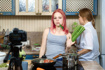 teenage girl with pink hair writes a video blog about healthy eating. celery in hands. Mom went...