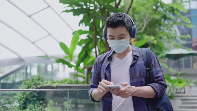 Traveler of Young Asian man wearing medical mask are walking around the city. Face mask prevent Coronavirus and PM2.5 Urban dust pollution. Travel on summer vacation. No lockdown on the tour.