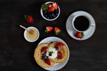 Pancakes with strawberries and blueberries and honey. Top view.