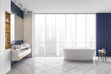 Obraz na płótnie Canvas Blue and white bathroom with bathtub and sinks with big mirror, grey tile floor