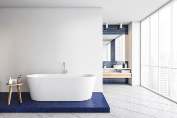 Fototapeta na wymiar Blue and white bathroom with bathtub and sinks on marble floor