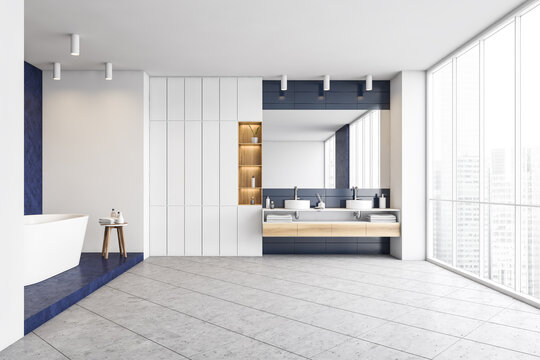 Blue and white bathroom with bathtub and sinks with big window, grey floor