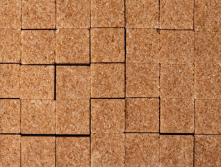 Fototapeta premium Brown cane sugar, cubes. Lie tightly next to each other. View from above. Close-up. Sugar crystals.