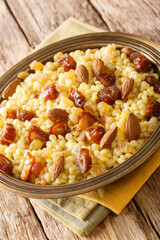 Mesfouf or masfouf is an Algerian, Moroccan and Tunisian dish which sweet couscous with dried fruits and nuts close-up in a plate on the table. vertical