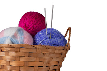 Balls of multi-colored knitting threads and knitting needles in a basket. Isolated on white background. Close-up. Copy space.