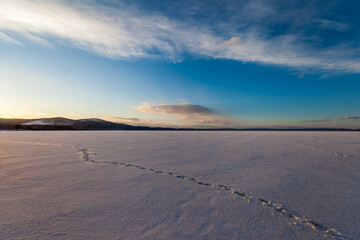 frozen lake in winter on a background of blue sky with clouds