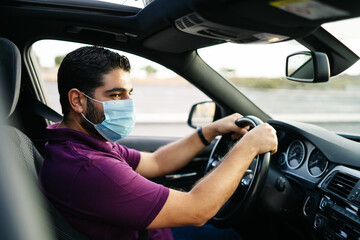 Fototapeta na wymiar Man driving a car wearing on a medical mask during a Covid-19 pandemic