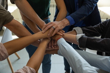 Fototapeta na wymiar Stacking palms. Motivated business people employees corporate team members of different age and race putting hands together demonstrating unity bonding connection promising help support, close up view
