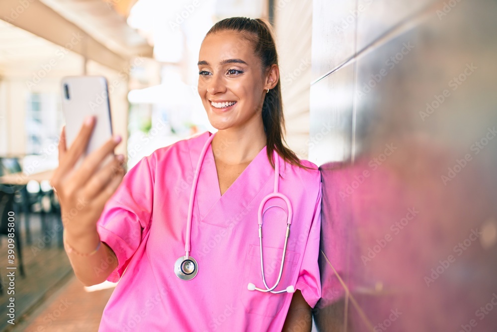 Wall mural young hispanic doctor woman speaking on the smartphone at street of city.