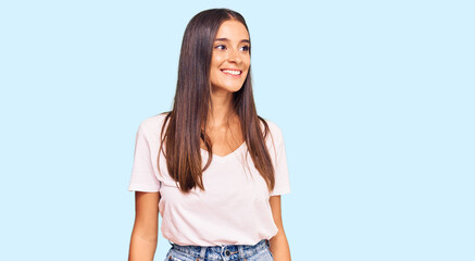 Young hispanic woman wearing casual white tshirt looking away to side with smile on face, natural expression. laughing confident.