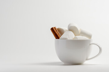 Cup of cocoa with marshmallows, cinnamon on white background.