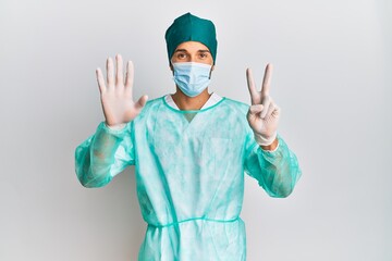 Young handsome man wearing surgeon uniform and medical mask showing and pointing up with fingers...
