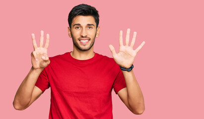 Naklejka premium Young handsome man wearing casual red tshirt showing and pointing up with fingers number eight while smiling confident and happy.