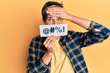 Young hispanic man covering mouth with insult message paper stressed and frustrated with hand on...