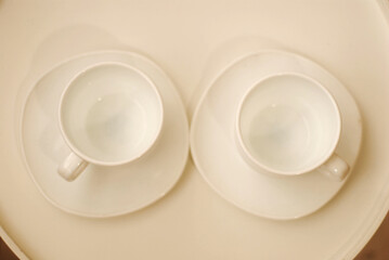 Two white cups on a white tray top view