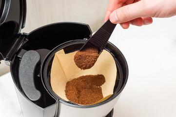 Process of making coffee from ground beans in a coffee maker - loading coffee into a paper  filter