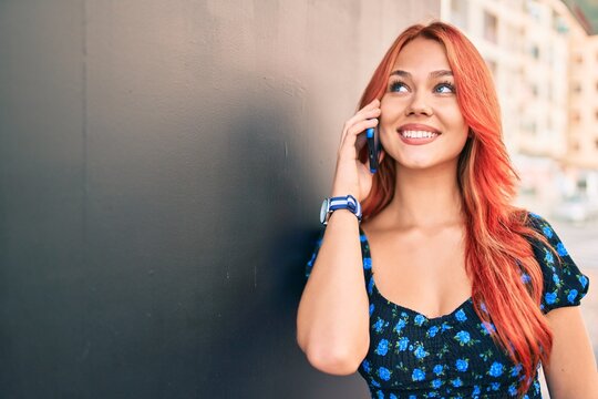 Young redhead girl smiling happy Talking on the smartphone at the city.