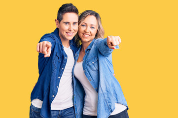 Couple of women wearing casual clothes pointing to you and the camera with fingers, smiling positive and cheerful