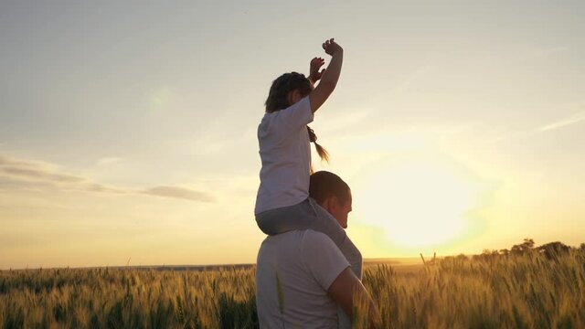 Happy family father and daughter in wheat field at sunset. Father and daughter play airplane pilot. Happy family raise their hands at sunset. Father with daughter airplane wings. Happy family concept