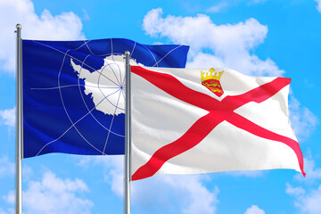 Jersey and Antarctica national flag waving in the windy deep blue sky. Diplomacy and international relations concept.