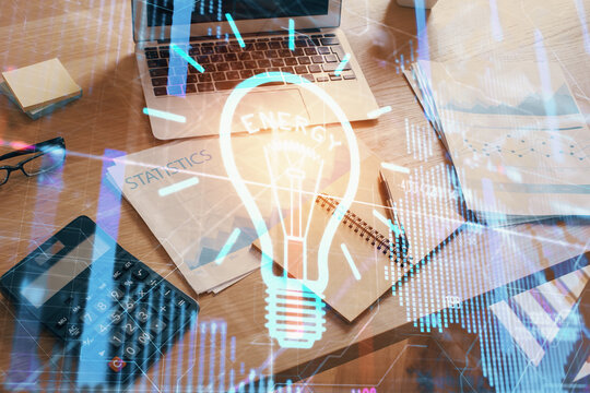 Computer on desktop in office with bulb icon hologram. Double exposure. Concept of idea.