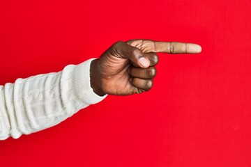 Fototapeta premium Arm and hand of african american black young man over red isolated background pointing with index finger to the side, suggesting and selecting a choice
