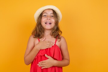 Fototapeta premium young Caucasian girl standing against yellow background keeps hands crossed, laughs out loud at good joke, wears casual clothes.