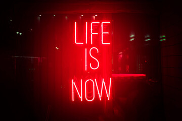 Red neon sign life is now. Glow quote about live and self motivation. Here and now abstract concept.