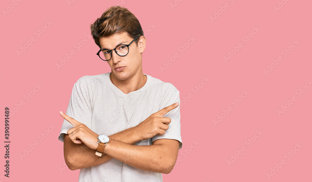 Wall mural Handsome caucasian man wearing casual clothes and glasses pointing to both sides with fingers, different direction disagree