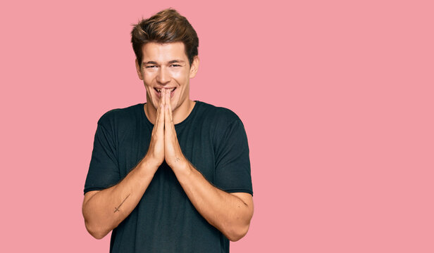 Handsome caucasian man wearing casual clothes praying with hands together asking for forgiveness smiling confident.