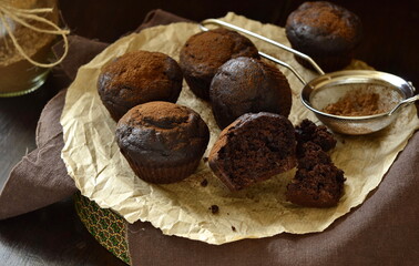 Chocolate banana muffin sprinkled with cocoa on dark background