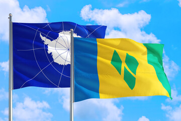 Saint Vincent And The Grenadines and Antarctica national flag waving in the windy deep blue sky....