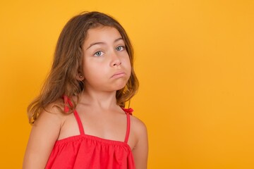 Caucasian young girl standing against yellow background with snobbish expression curving lips and...