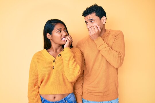 Beautiful latin young couple wearing casual clothes together looking stressed and nervous with hands on mouth biting nails. anxiety problem.