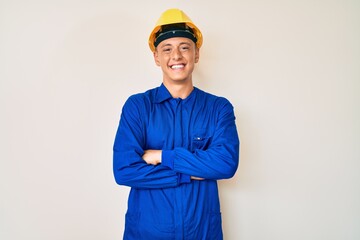 Young hispanic boy wearing worker uniform and hardhat happy face smiling with crossed arms looking at the camera. positive person.