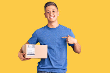 Young handsome hispanic man holding delivery package pointing finger to one self smiling happy and...