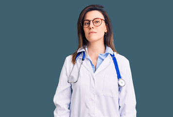 Young beautiful woman wearing doctor stethoscope and glasses relaxed with serious expression on face. simple and natural looking at the camera.