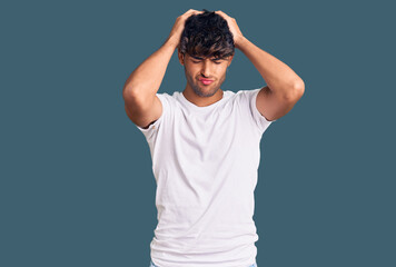 Young hispanic man wearing casual clothes suffering from headache desperate and stressed because pain and migraine. hands on head.