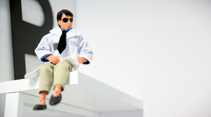Small Miniature Model Of A Doctor Sitting On A Shelf With Copy Space Background