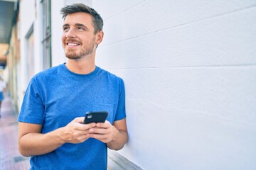 Young caucasian man smiling happy using smartphone at the city.