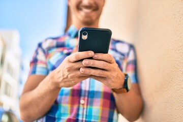 Young caucasian man smiling happy using smartphone at the city.