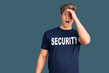 Young handsome man wearing security t shirt surprised with hand on head for mistake, remember...
