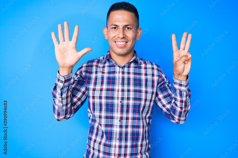 Wall mural young handsome latin man wearing casual clothes showing and pointing up with fingers number eight wh