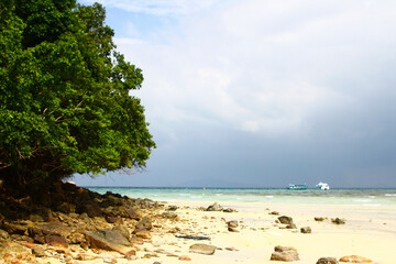 Fototapeta na wymiar Beautiful landscape view of beach and tree with blue sky, white cloud, raining and boat on sea background with copy space in south of Thailand. Beauty in nature and Natural wallpaper.
