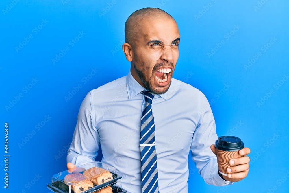 Sticker Hispanic adult business man holding take away coffee and sweets angry and mad screaming frustrated and furious, shouting with anger. rage and aggressive concept.