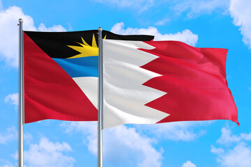 Bahrain and Antigua and Barbuda national flag waving in the windy deep blue sky. Diplomacy and international relations concept.