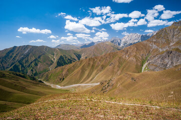 Rocky pass with mountain top views in high mountains. Young men and women hiking near Sary Chelek lake, Sary-Chelek Jalal Abad region, Kyrgyzstan, Trekking in Central Asia.