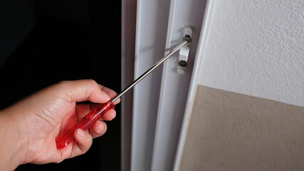 Locksmith in installing new house door lock hand holds the screwdriver