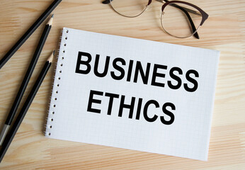 In the notebook is the text of BUSINESS ETHICS, next to pencils and glasses.